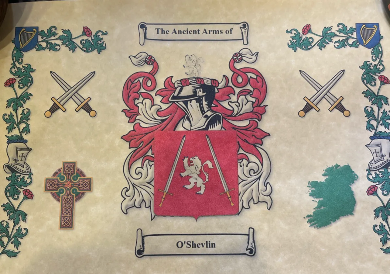 The Ancient Arms of O'Shevlin: a silver lion rampant between two swords on a red shield, beneath a knight's helm, framed by Celtic crosses, crossed swords and a map of Ireland